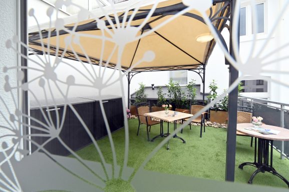 Attraktive Terrasse mit Überdachung und Sitzmöbeln mit Tisch.