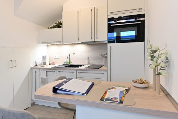 Moderne Küchenzeile mit Spüle, Herd und Kühlschrank, ergänzt durch einen kleinen Tisch.