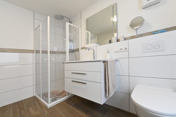 Badezimmer mit bodentiefer Dusche und Regenbrause.