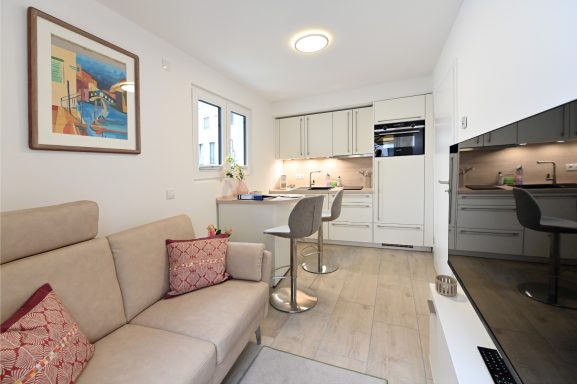 Wohn- Essbereich mit gemütlichen und hochwertigen Möbeln, Fernseher und direkter Zugang zur Terrasse.
